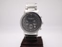 Front view of the Rocha John Rocha chronograph watch on a display stand, dark grey dial and stainless steel bracelet.