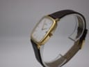 Angled side view of the gold-plated Citizen watch on a display stand, showing the crown.