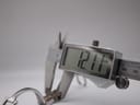 Close-up shot showing callipers measuring the width of the Gucci 1500L watch case, displaying "12.11 mm" on the digital screen.