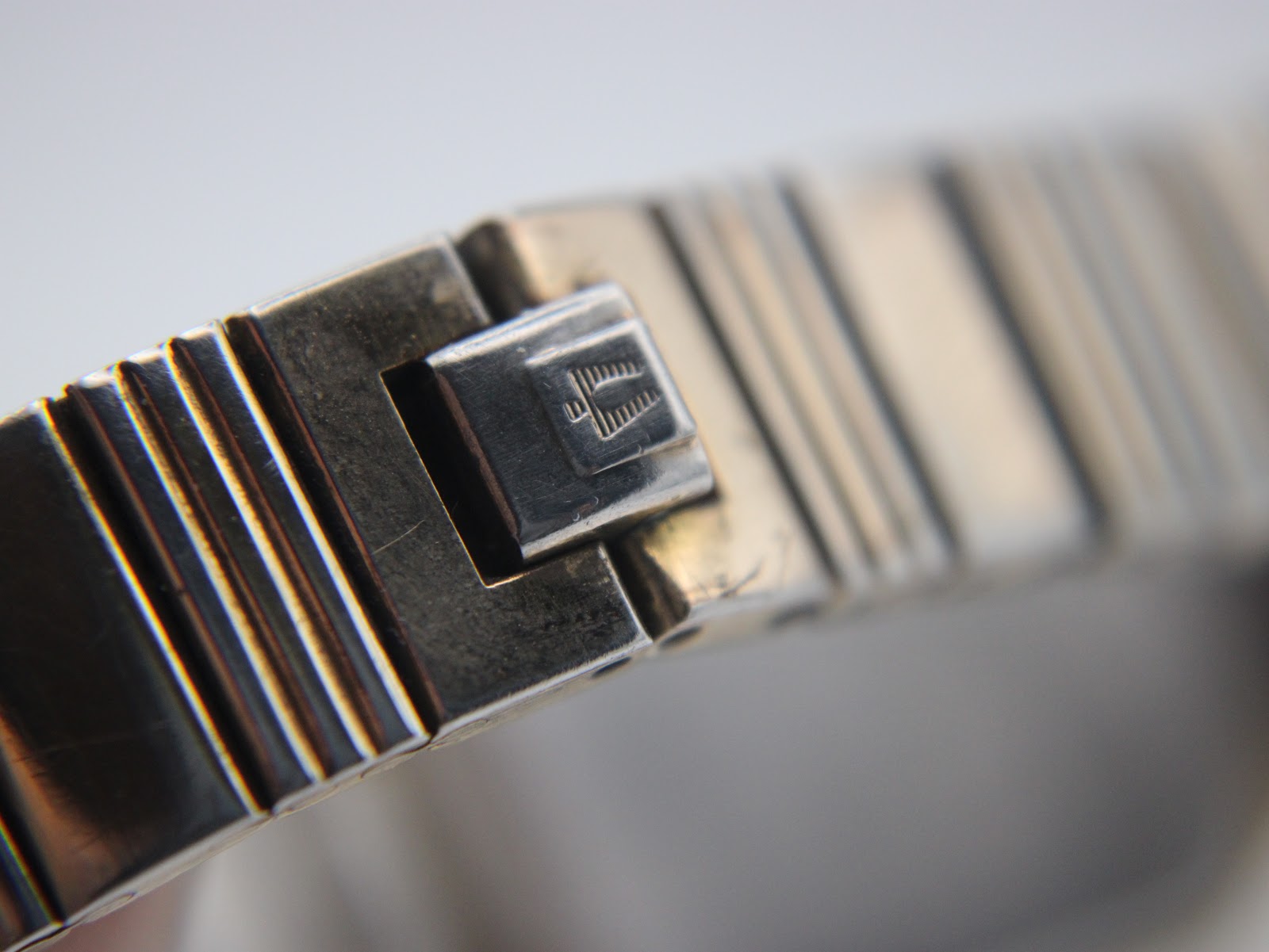 Macro shot of the signed folding clasp on the Bulova watch bracelet, showing the engraved logo.