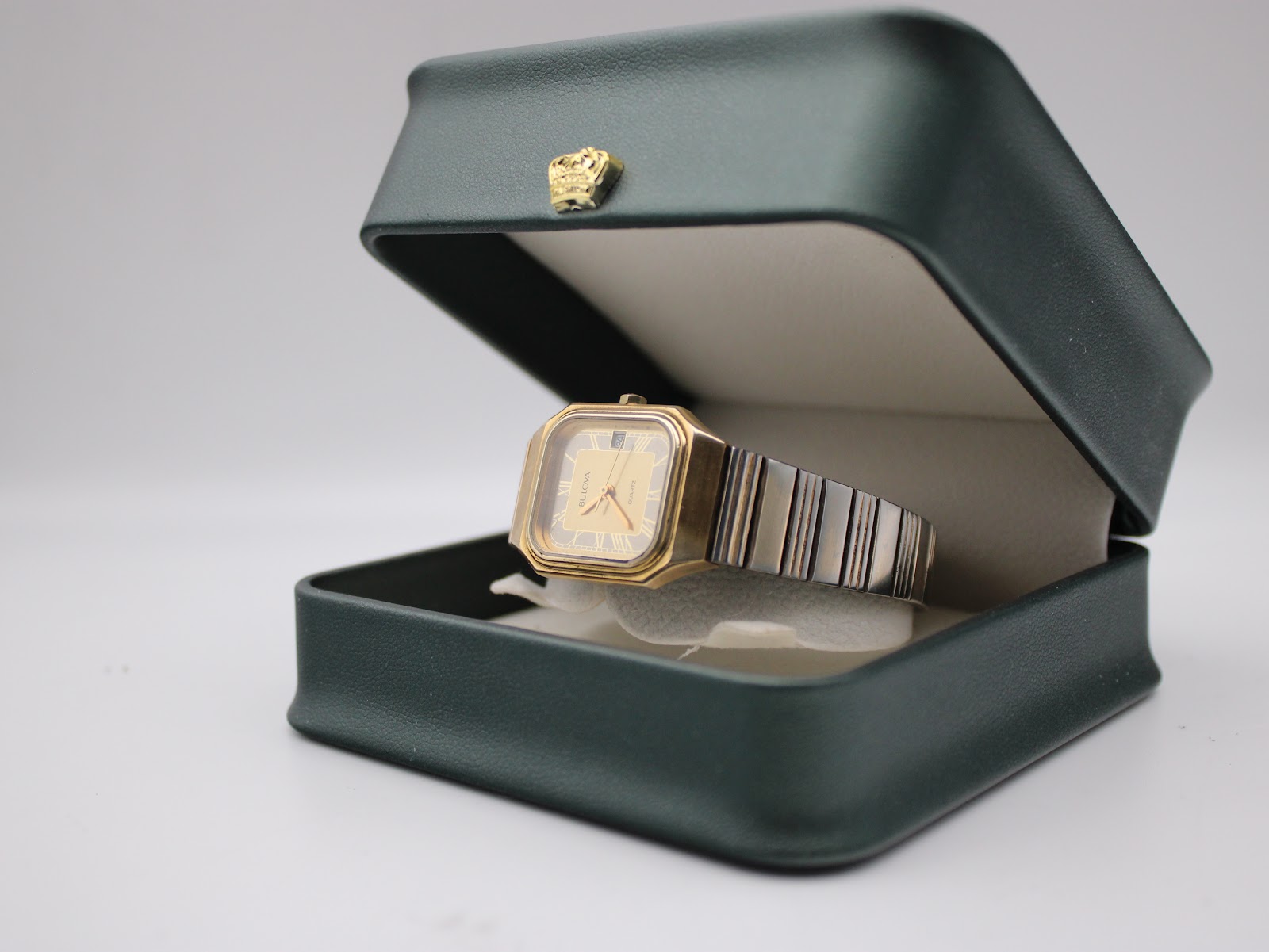 Bulova P2 watch resting inside an open dark green presentation box with a gold crown emblem.