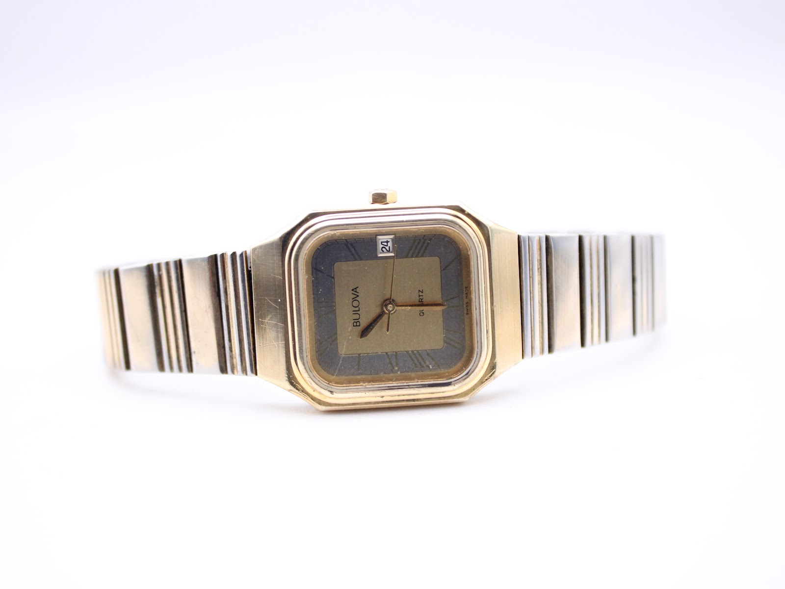 Angled front perspective of the Bulova P2 watch with its gold tone bracelet laid out.