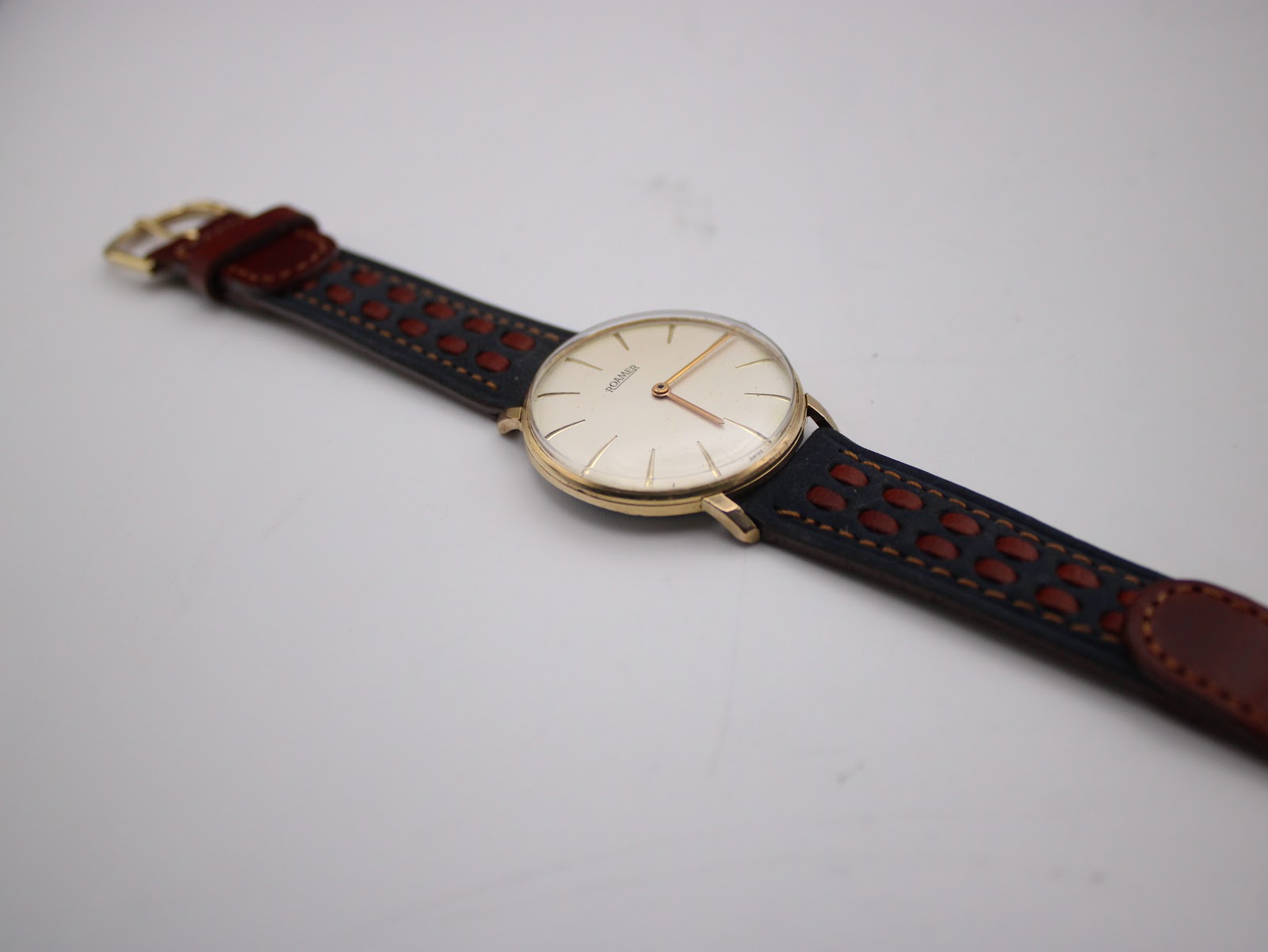 Angled view of the Roamer watch and its racing style two-tone leather strap, emphasizing the perforations and contrasting colours.