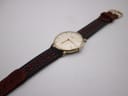 Full view of the Roamer watch on a display stand, presenting the entire length of its two-tone perforated leather strap.