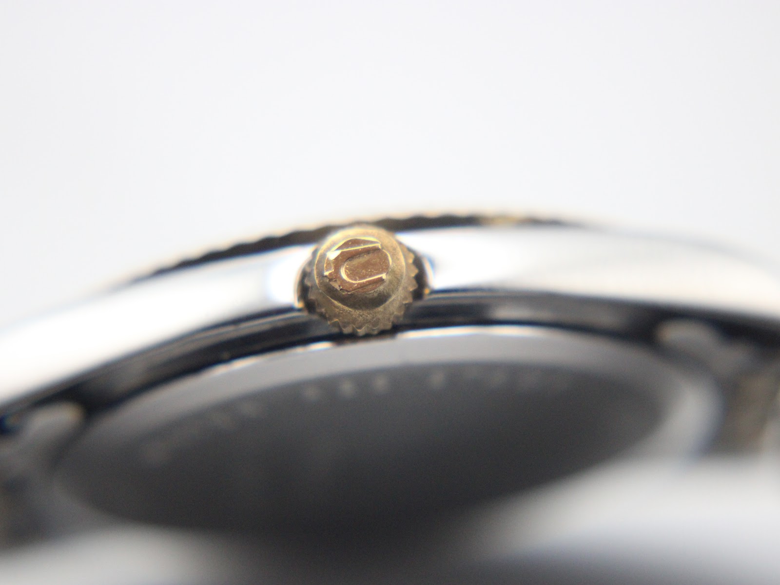 Extreme close-up of the gold-tone crown, showing the Bulova tuning fork logo.