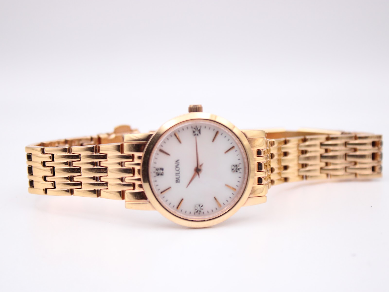 Horizontal full view of the Bulova 97P106 watch and its rose gold tone integrated steel bracelet on a display stand.