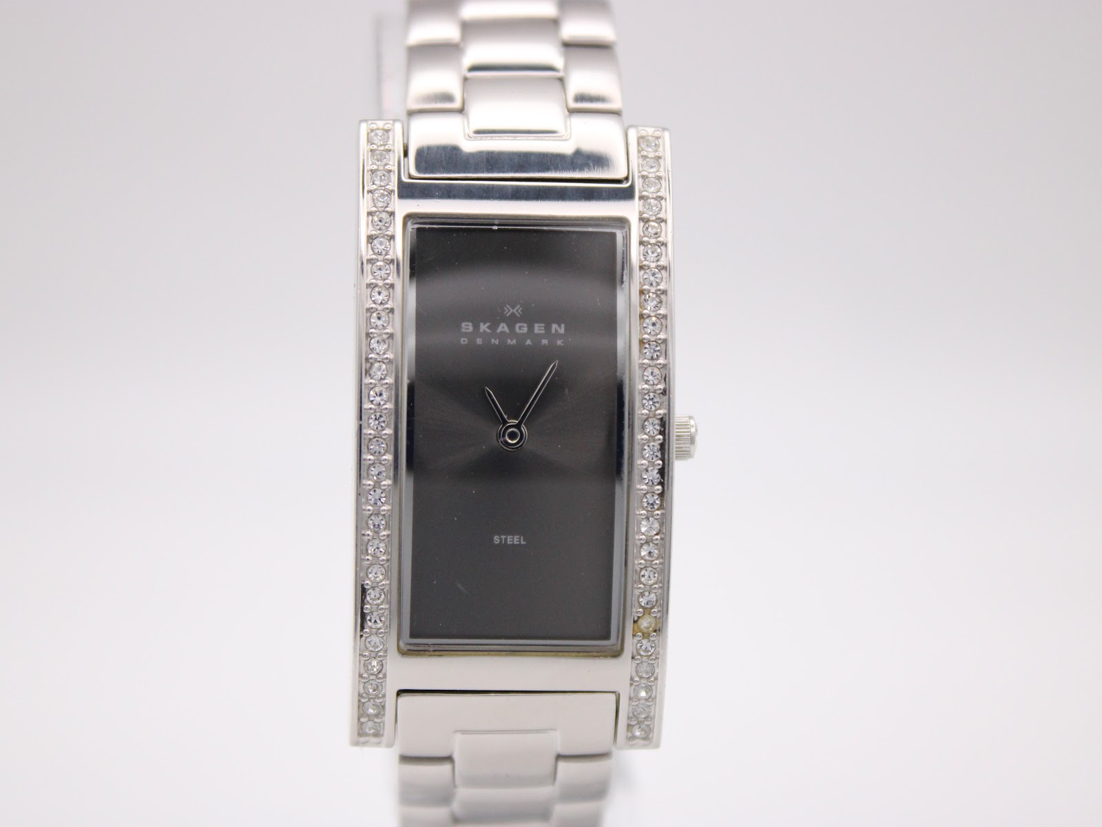 Close-up front view of the Skagen Denmark 459SSXM watch dial, showing the Skagen logo, "DENMARK", and "STEEL" text on the minimalist black face with silver hands.