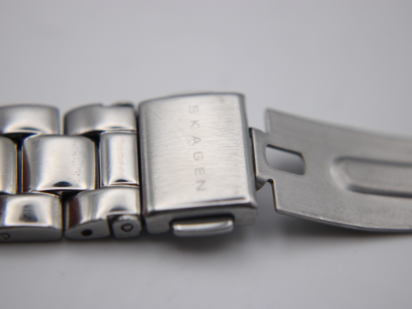 Close-up of the stainless steel bracelet's fold-over clasp, clearly showing the "SKAGEN" brand name engraved vertically.