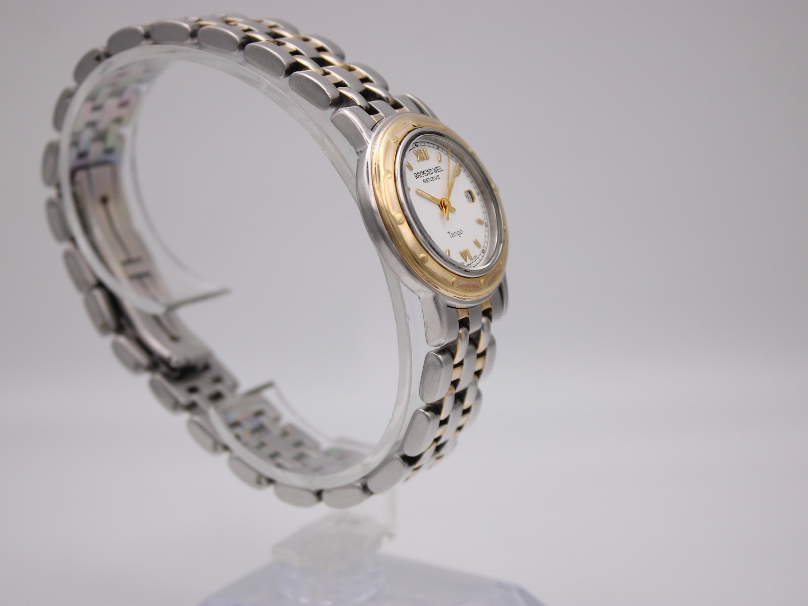 Three-quarter view of the Raymond Weil Tango, showing the gold-plated bezel and the two-tone steel bracelet.