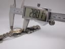 A digital caliper measuring the watch case diameter, displaying an exact measurement of 28.01mm.