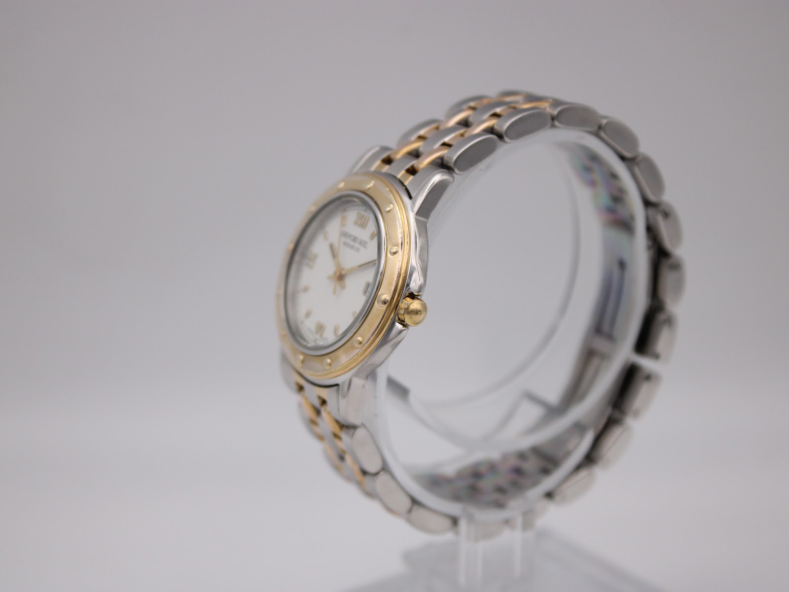 Side view of the Raymond Weil Tango watch, showing the gold crown and two-tone bracelet.
