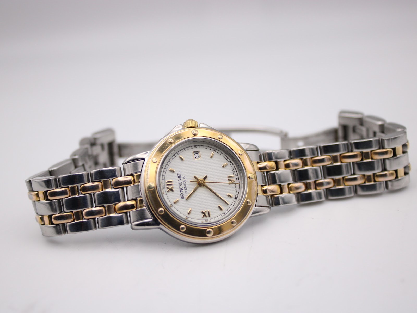 Top-down angled view of the Raymond Weil Tango watch, with the two-tone bracelet laid flat.