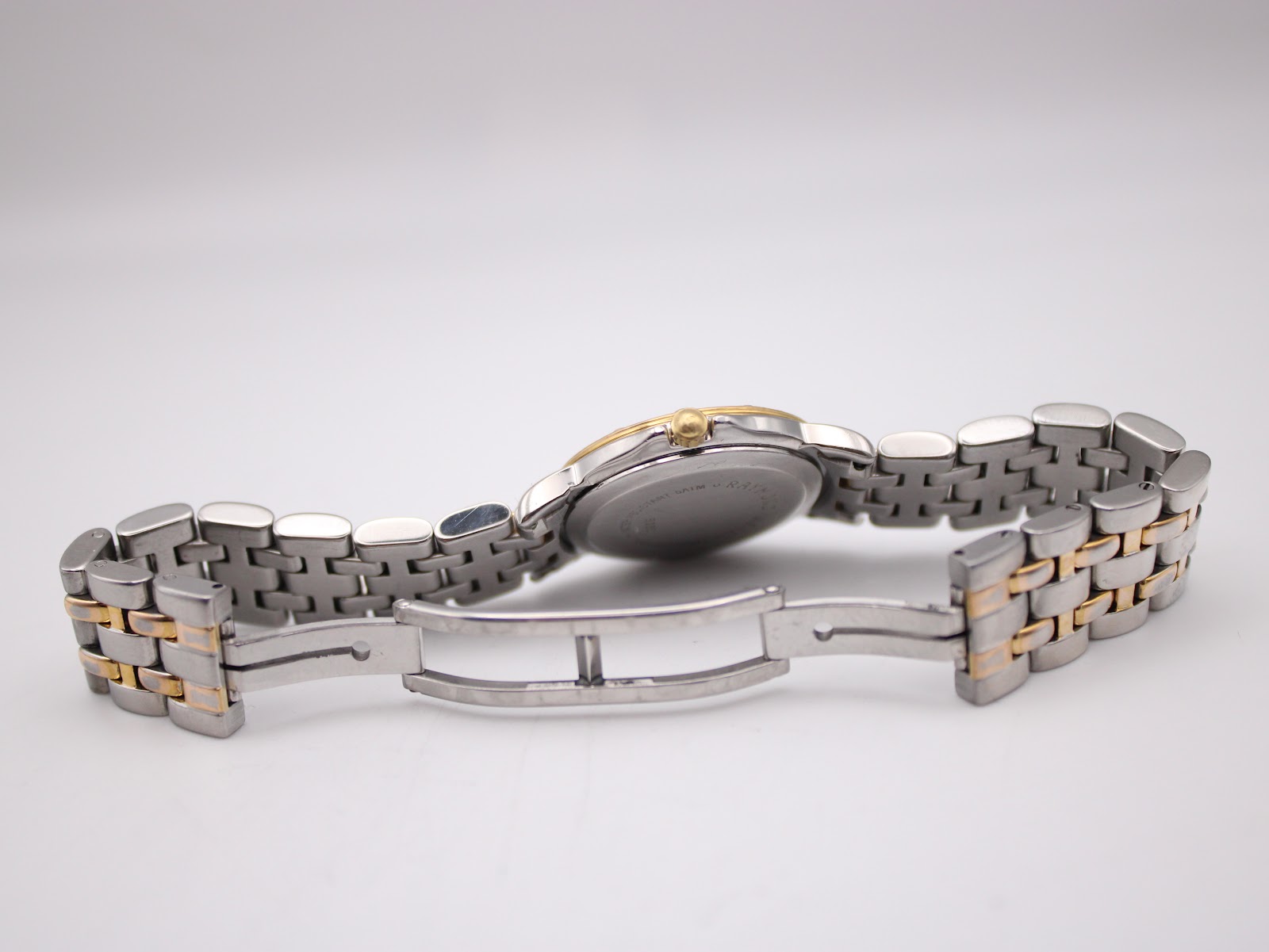 Rear view of the open two-tone bracelet and deployant clasp, showing the case back and bracelet links.