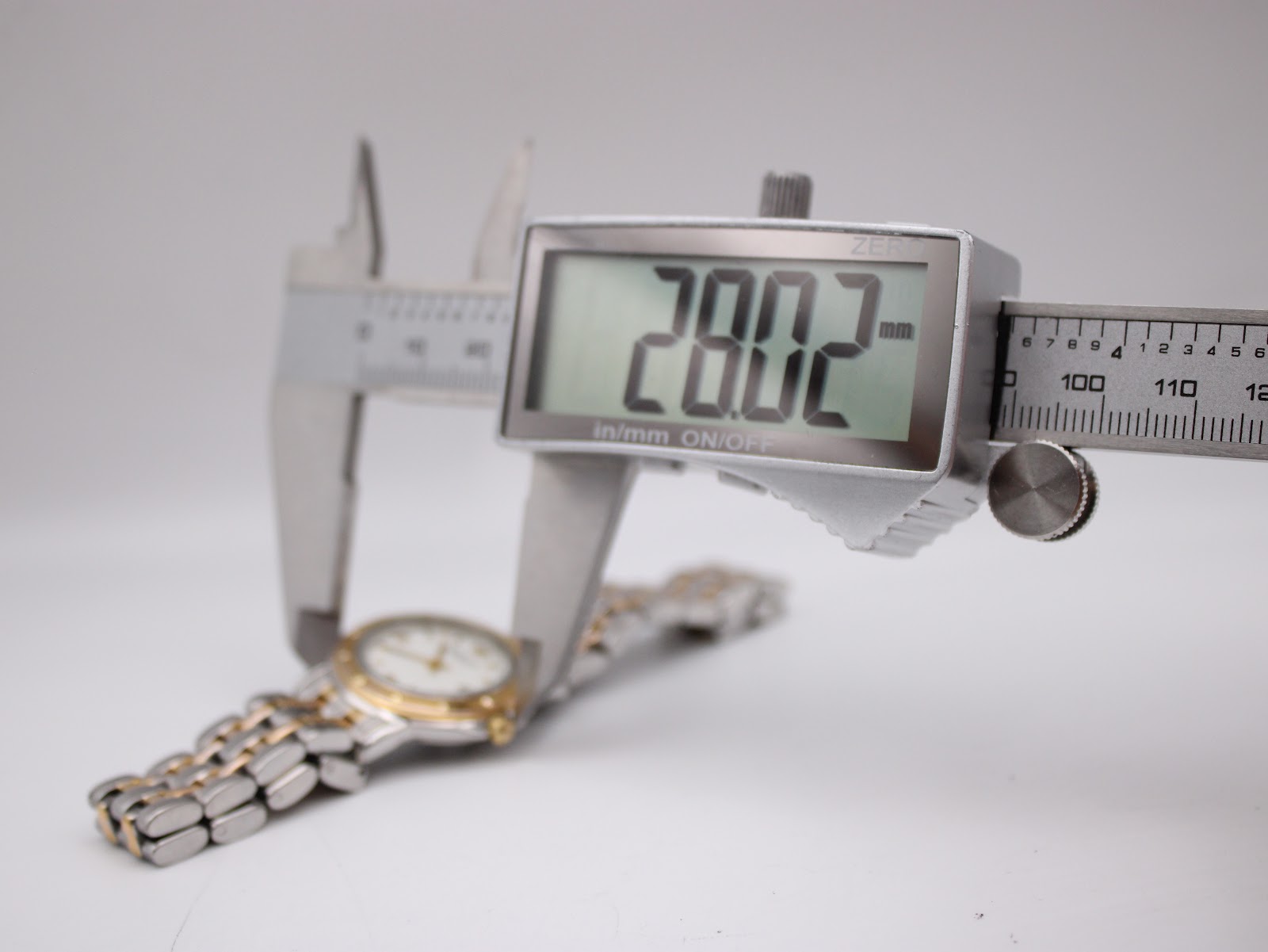 Digital caliper measuring the watch case diameter at 28.02mm.