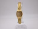 Front view of the gold Raymond Weil 5707 ladies' quartz watch with champagne dial and woven bracelet on a clear stand.