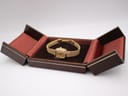 The Raymond Weil watch nestled within an open brown hinged watch box with a velvet interior.