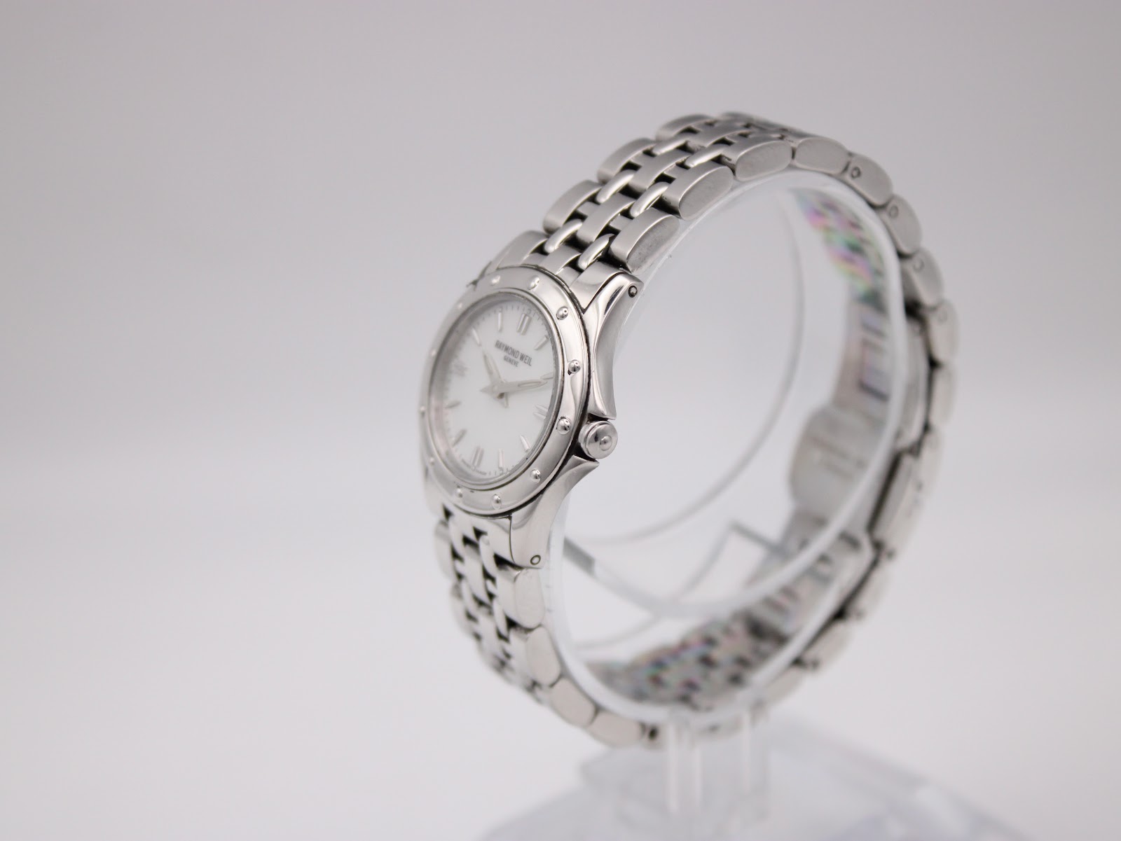 Right side angle view of Raymond Weil Tango watch on a clear stand, showcasing the watch's profile and crown.