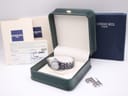 Raymond Weil Tango watch nestled in a dark green presentation box, with its instruction papers, guarantee card, and extra bracelet links visible.