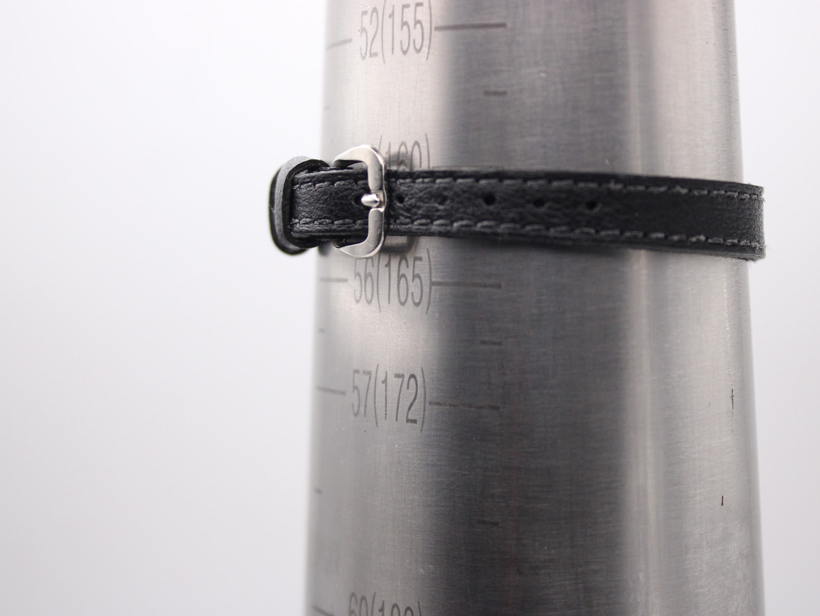 Close-up of the black leather strap with silver-tone buckle on a wrist sizing gauge, indicating a wrist fit of approximately 165mm.