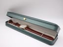 The Raymond Weil watch nestled in an open green watch box against a white background.