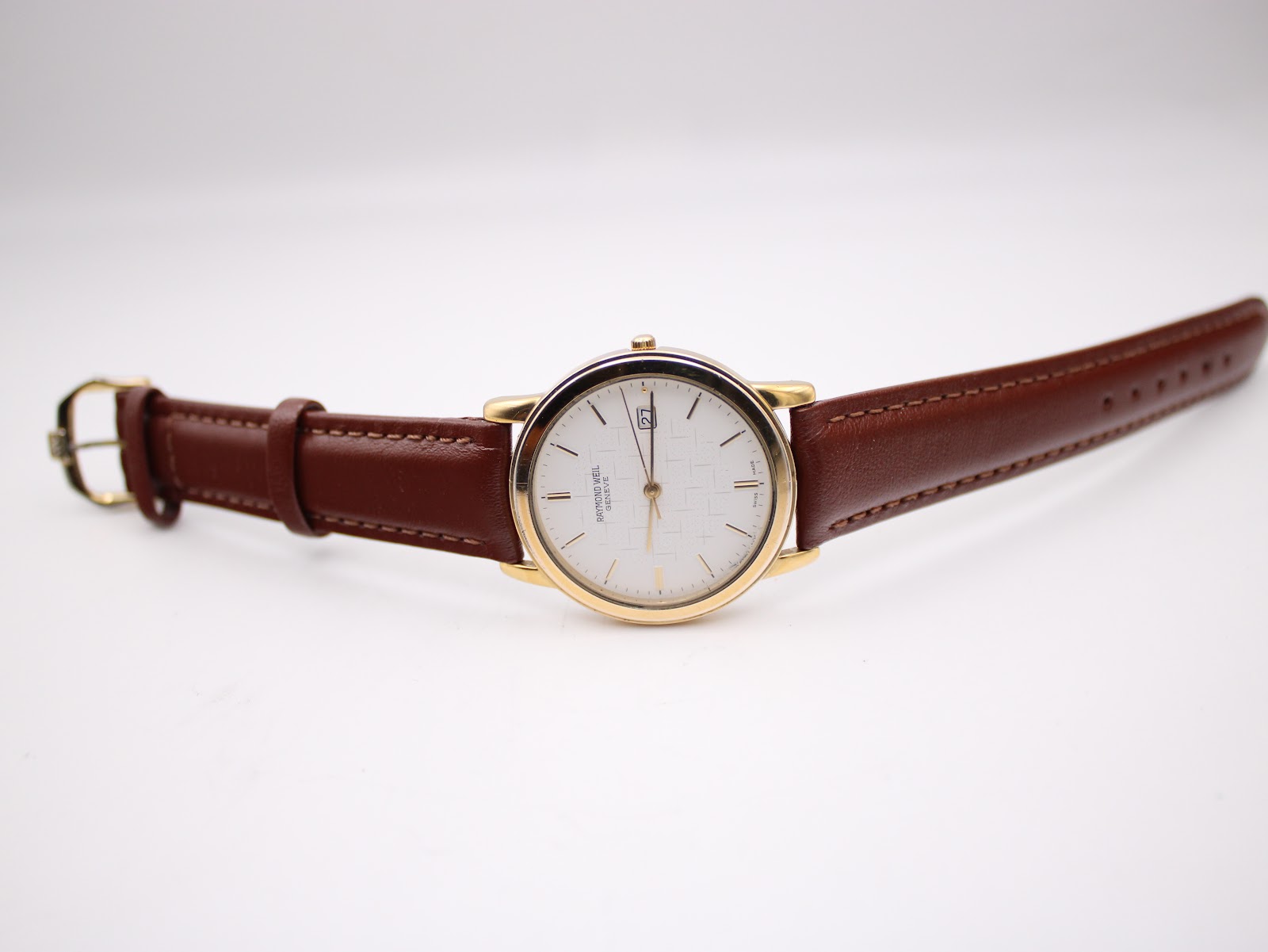 Full watch spread out, showing the brown leather strap and gold tone case on a white background.