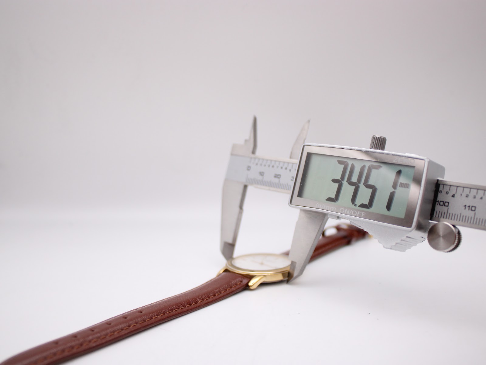 Digital caliper measuring the watch case diameter, displaying 34.51mm.