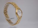 Another oblique side view of the gold Raymond Weil watch and its 'rice bead' style bracelet on a clear display stand.