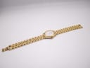 Full length view of the gold Raymond Weil watch and 'rice bead' bracelet laid flat, showing the front of the watch.