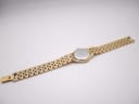 Full length view of the gold Raymond Weil watch and bracelet laid flat, showing the case back.
