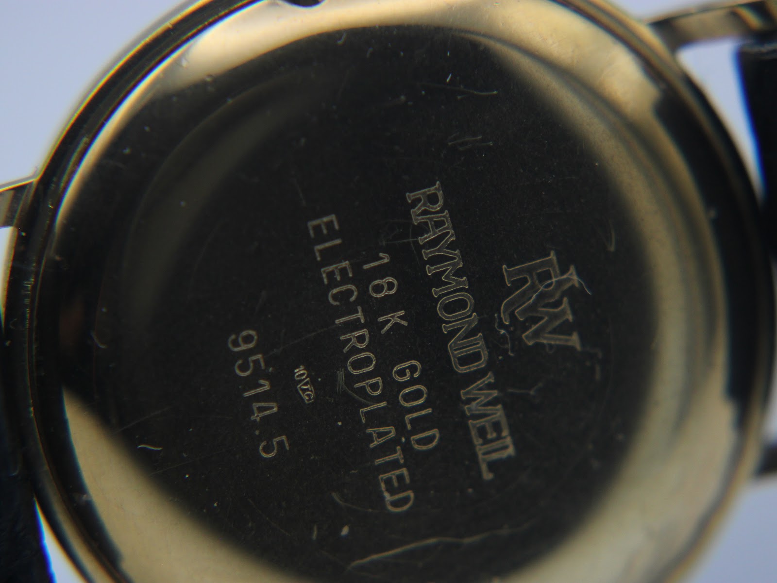 Close-up of the watch's gold case back, showing engravings for 'Raymond Weil', '18K GOLD ELECTROPLATED', and '9514.5'.