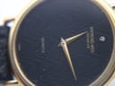Macro shot of the black textured dial with a subtle wave pattern, gold tone hands, and the single diamond marker at 12 o'clock.