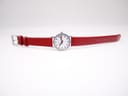 Overhead view of the Mondaine watch with the red leather strap laid flat.