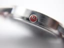 Close-up of the watch crown showing the red M-logo detail.