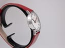 Three-quarter view of the Mondaine watch, showing the dial, case profile, and strap from a slight angle.