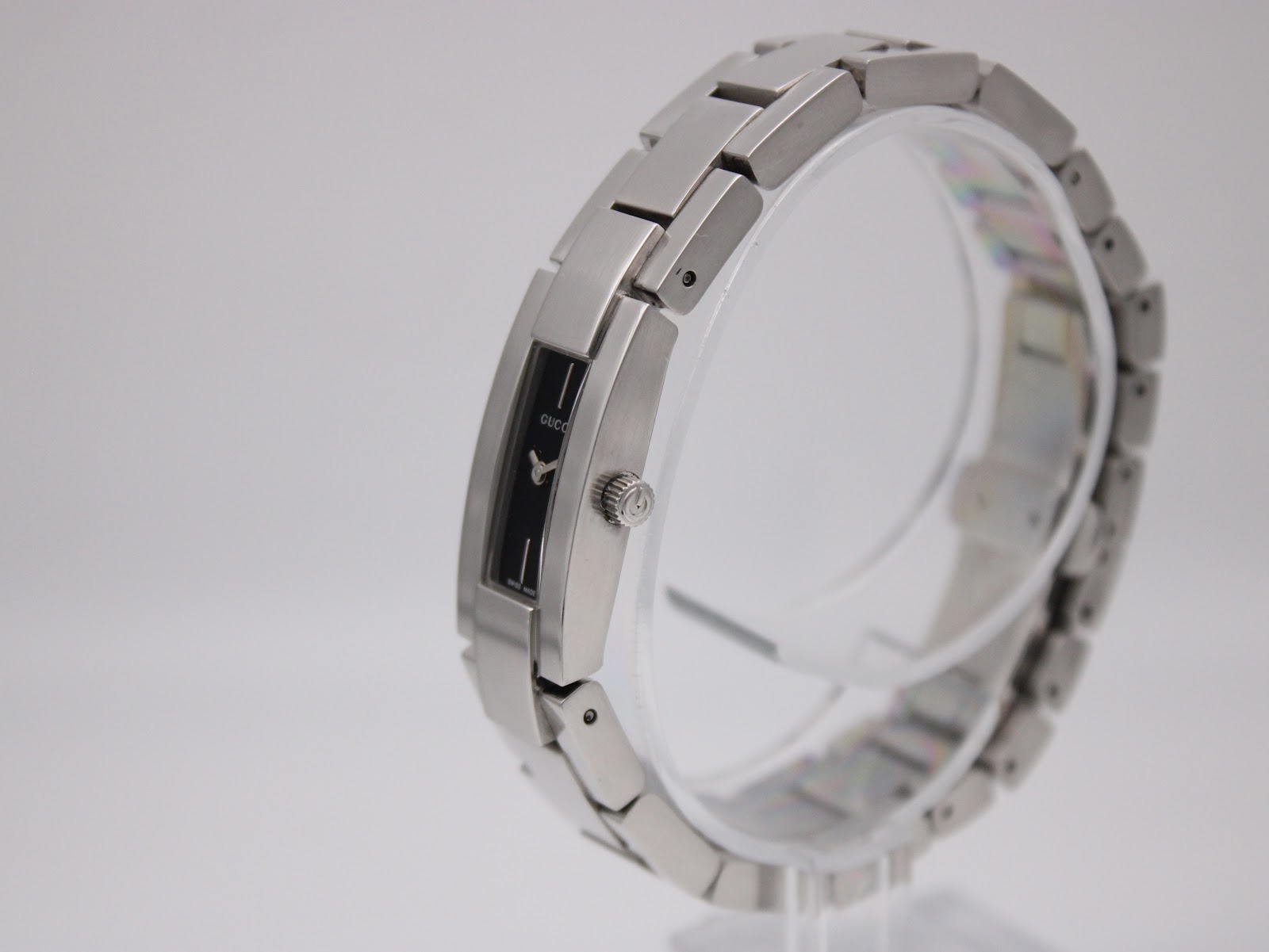 Oblique side view of the Gucci 4600L on a clear display stand, highlighting the bracelet links and slender case profile.