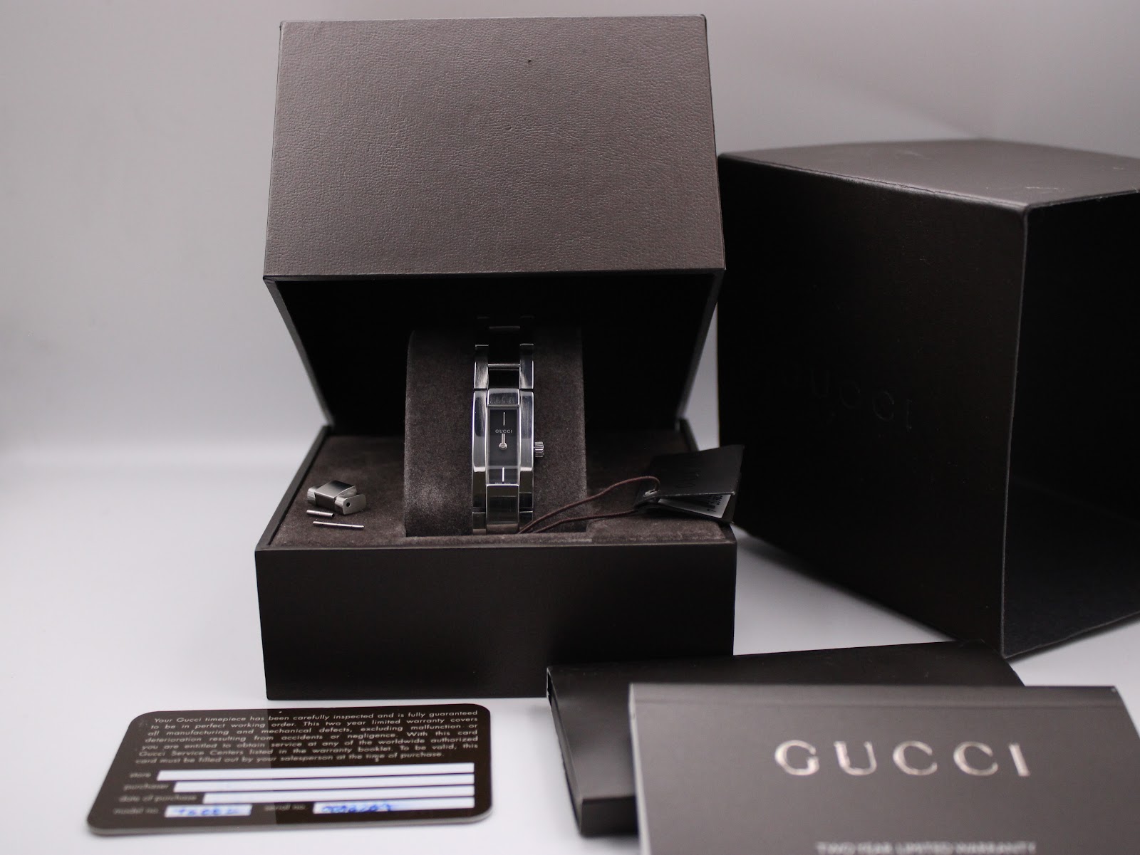 Gucci 4600L watch presented in its original black box, with the authenticity card, manual, and extra bracelet links visible.