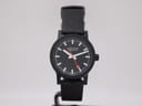 Another side view of the black Mondaine watch on a display stand, highlighting the minimalist design