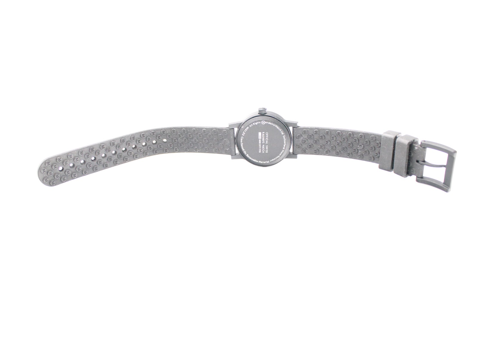 Bottom-up view of the Mondaine watch with its black rubber strap extended, showing the textured underside and case back