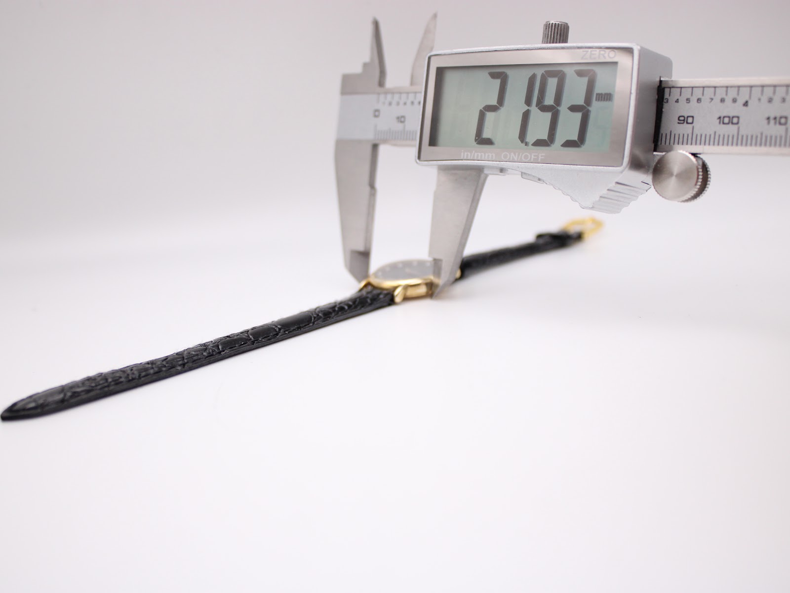 A digital caliper measuring the case diameter of the watch, displaying an exact measurement of 21.93 mm.