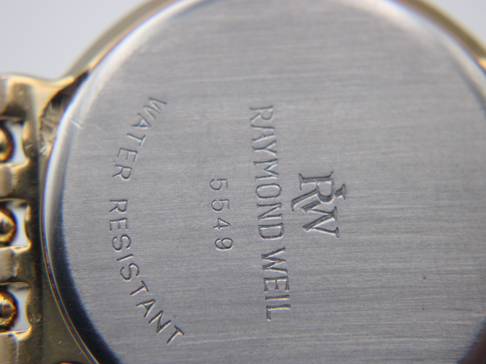 Close-up of the watch's stainless steel case back with engraved 'Raymond Weil Genève 5549' and 'Water Resistant' text.