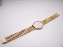 Overhead view of the Raymond Weil watch with its integrated two-tone bracelet extended on a flat surface.