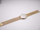 Full view of the watch from the back, showing the case back and the entire length of the gold and silver tone bracelet.