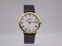 Front view of Raymond Weil Geneve 5507-2 watch with gold case, white dial, roman numerals, and dark brown leather strap.
