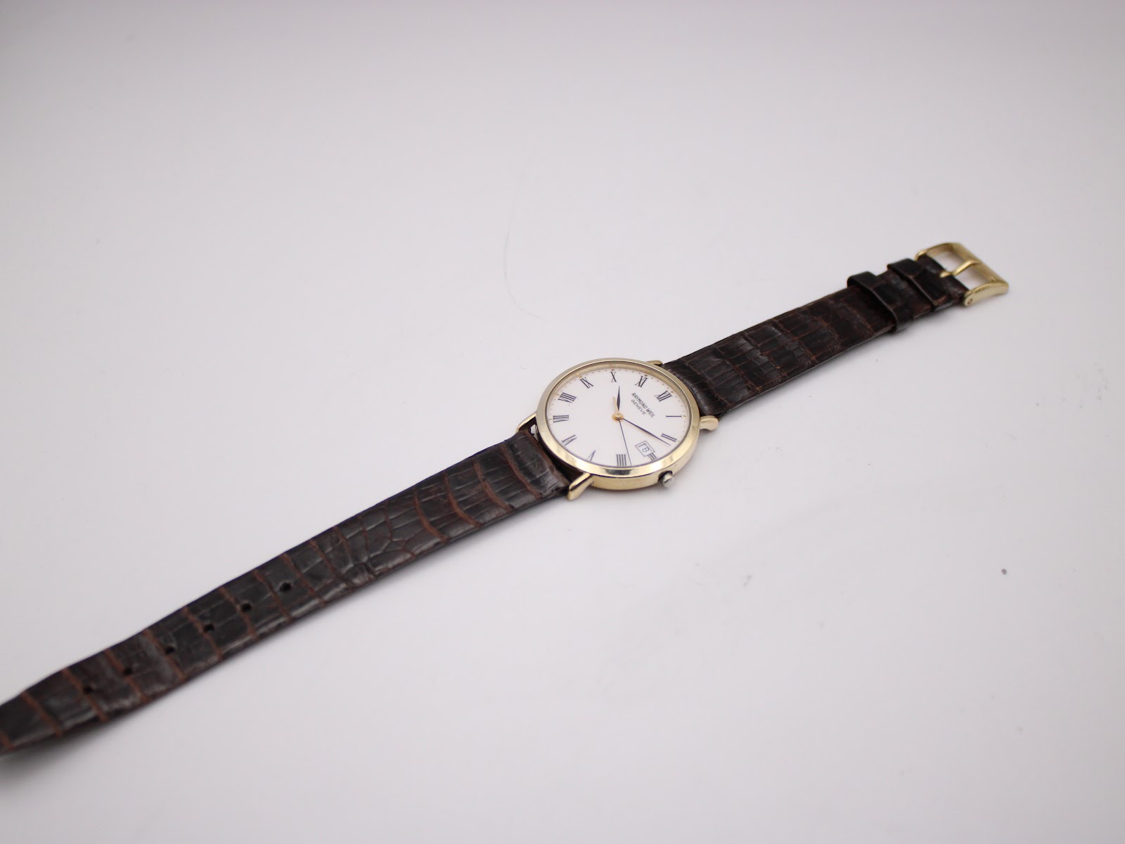 Full length view of the Raymond Weil watch with its brown crocodile-embossed leather strap laid flat on a white background.