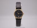 Front view of Raymond Weil Geneve ladies' watch with gold electroplated case, black diamond dial, and dark brown leather strap, displayed on a clear stand.