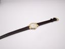 Full length view of the Raymond Weil watch with its dark brown lizard-style leather strap unbuckled on a white background.