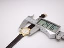 Digital caliper measuring the case diameter of the Raymond Weil watch, displaying an exact measurement of 24.16mm.