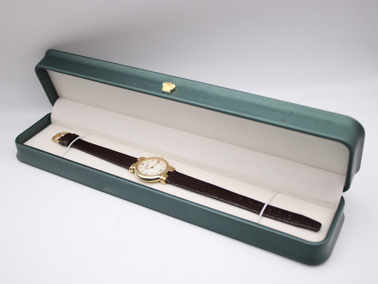The Raymond Weil Geneve watch nestled inside its original dark green presentation box with a cream-coloured interior lining.