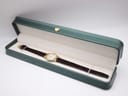 The Raymond Weil Geneve watch nestled inside its original dark green presentation box with a cream-coloured interior lining.