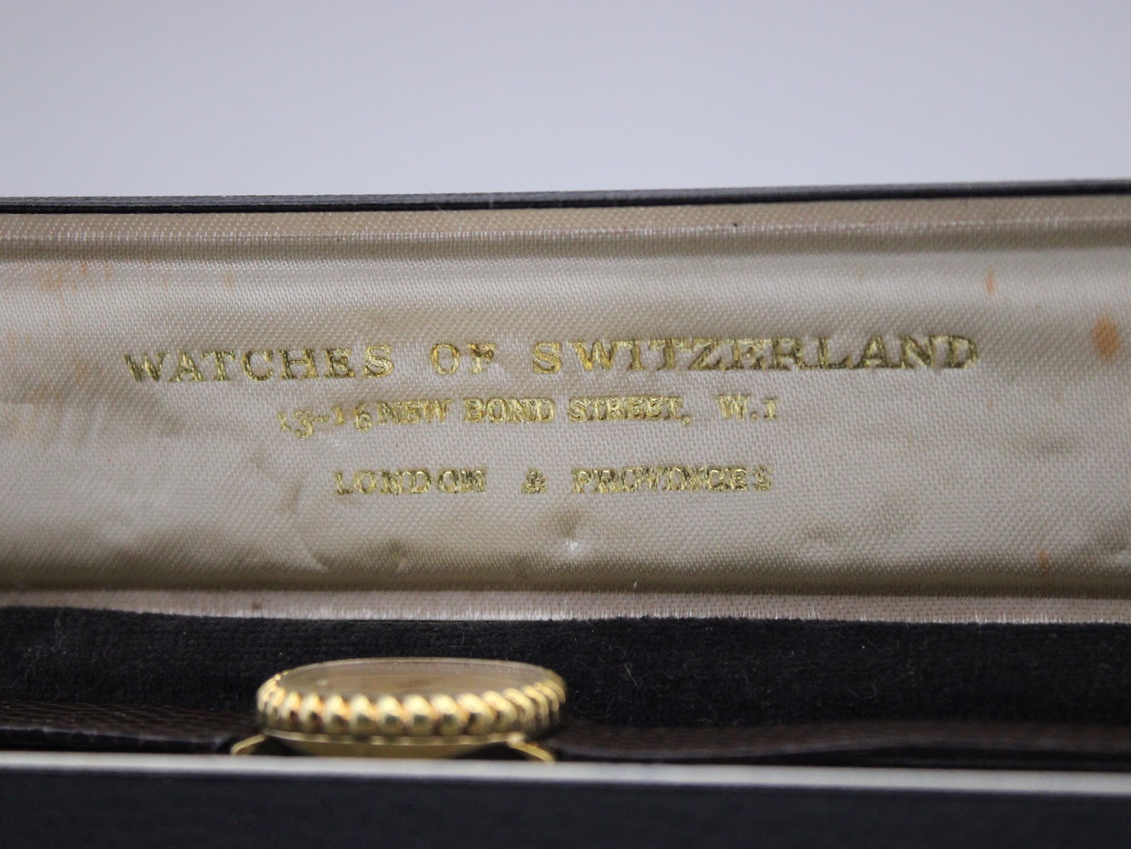 Close-up of the 'Watches of Switzerland 16 New Bond Street' gold lettering inside the vintage watch box.